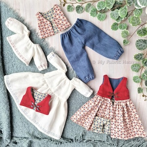 May include: A set of doll clothes including a white dress with embroidered hearts, a red and white checked waistcoat, a pair of blue denim trousers, and a red and white checked dress with a red waistcoat.