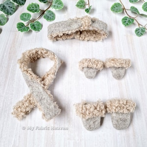 Könnte beinhalten: Ein Set aus Zubehör, bestehend aus einem Stirnband, einem Schal und zwei Paar Fäustlingen, gefertigt aus grauem Filzstoff mit beigem, lockigem Kunstfellbesatz. Der Text My Fabric Heaven ist in der unteren linken Ecke zu sehen.