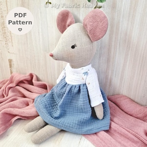 May include: A handmade fabric mouse doll with a light beige body, pink ears, and a red nose. It wears a white top with blue floral accents and a blue dress. The image includes the text "PDF Pattern".