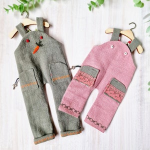 Puede incluir: Dos pares de pantalones de peto para niños, uno en verde con una zanahoria bordada y el otro en rosa con ribete de encaje.