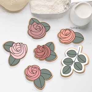 May include: Six cookie cutters in the shape of roses and a sprig of leaves. The cutters are made of metal and have a silver finish. The roses are pink and the leaves are green.