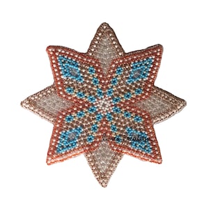 Op de afbeelding: Een stervormige ornament van kralen met een geometrisch patroon in tinten oranje, blauw en wit. De ornament is gemaakt van kleine kralen en heeft een glanzende, iriserende afwerking.