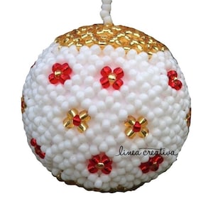 Pode incluir: Enfeite de Natal branco com flores vermelhas e douradas. O enfeite é feito de contas e tem um topo dourado.