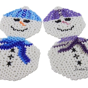 Pode incluir: Dois enfeites de boneco de neve de contas brancas com chapéus e cachecóis azuis e roxos. O boneco de neve à esquerda tem um chapéu e um cachecol azuis, enquanto o boneco de neve à direita tem um chapéu e um cachecol roxos. O texto "linea creativa" é visível no canto inferior direito da imagem.