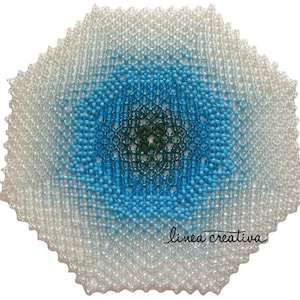 May include: A white, blue, and green beaded doily with a hexagonal shape and a gradient pattern. The doily has a "linea creativa" signature in the lower right corner.