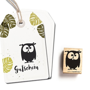 May include: White gift tags featuring a black owl illustration and the word "Gutschein". Green leaf accents and a wooden stamp with a matching owl design. The stamp has the text "cats on appletrees".