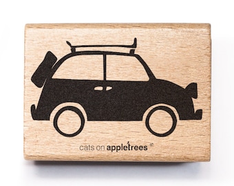 Pode incluir: Um carimbo de borracha preto e branco de um carro com uma prancha de surf no topo. O carimbo é feito de madeira e tem o texto "cats on appletrees" na parte inferior.