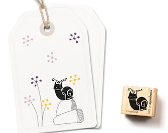 Puede incluir: Un sello de goma de madera con una ilustración en blanco y negro de un caracol en una roca. El sello está etiquetado como "Ermelund" y "cats on appletrees".