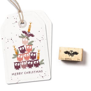 May include: White gift tags with a Christmas tree design made of owls, candles, and pine needles. The words "MERRY CHRISTMAS" are printed at the bottom. A wooden stamp with an owl design is also included.