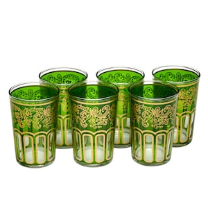 May include: A set of six green drinking glasses with gold filigree patterns. The glasses are cylindrical with a flared rim and gold trim. The gold design features floral and geometric motifs, adding a touch of elegance.