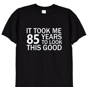 May include: Black t-shirt with white text that reads "It took me 85 years to look this good."