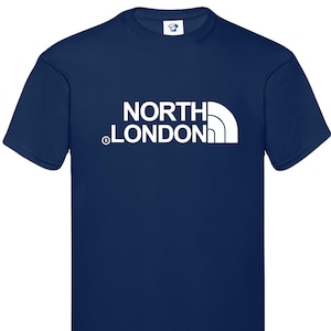 Peut inclure: Un t-shirt bleu marine avec un motif blanc représentant une chaîne de montagnes et le texte "NORTH LONDON" avec un symbole de marque déposée.