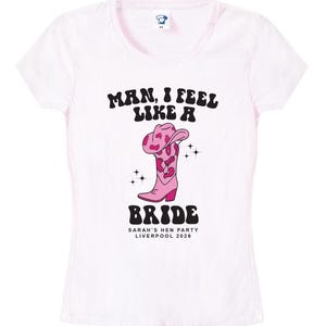 May include: Pink t-shirt with the text "Man, I feel like a Bride" in a retro font. The shirt also features a pink cowboy boot with a pink and white cow print design and the text "Sarah's Hen Party Liverpool 2026".
