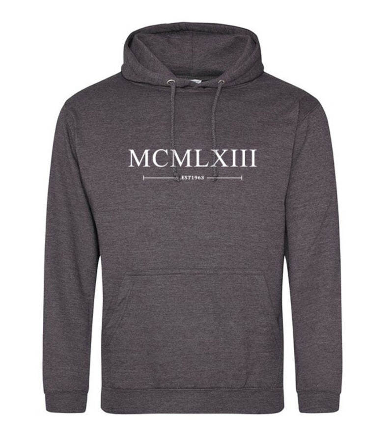 Puede incluir: Una sudadera con capucha gris oscuro con una impresi&oacute;n blanca que dice "MCMLXIII EST 1963".