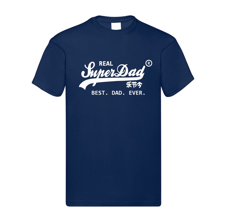 May include: A navy blue short-sleeved t-shirt featuring white screen-printed text that reads REAL SuperDad with a registered trademark symbol, Chinese characters, and the phrase BEST. DAD. EVER. centered on the chest area of the garment.