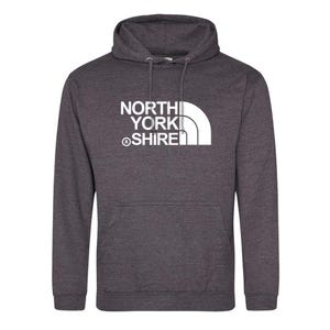 May include: A dark charcoal heather grey hooded sweatshirt featuring a white graphic print on the chest. The text reads NORTH YORK SHIRE with a registered trademark symbol and a stylized white quarter-circle graphic design element.