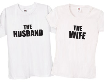 Może przedstawiać: Dwie białe koszulki z czarnym nadrukiem. Jedna koszulka ma napis "The Husband", a druga "The Wife".