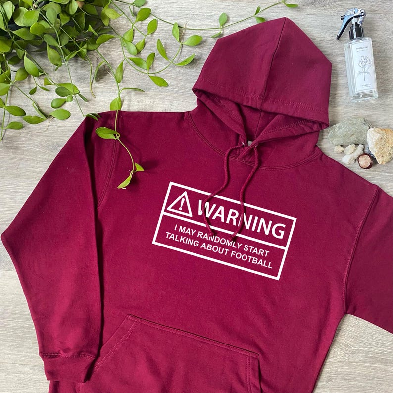 May include: A maroon hoodie with a white warning sign that says "WARNING I MAY RANDOMLY START TALKING ABOUT FOOTBALL"