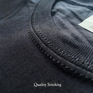 May include: Close-up of the neckline of a black t-shirt, showing the quality stitching. The stitching is a fine, even line, indicating a well-made garment.