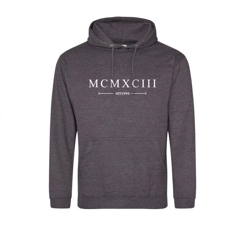 K&ouml;nnte beinhalten: Ein dunkelgrauer Kapuzenpullover mit dem Aufdruck "MCMXCIII EST 1993" in Wei&szlig; auf der Vorderseite.