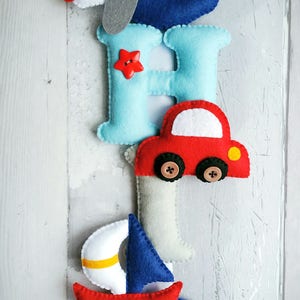 May include: Felt letter banner with the letters C, H, I, P, each decorated with a different transportation theme: airplane, car, sailboat, and a star. The letters are blue, light blue, gray, and dark blue.