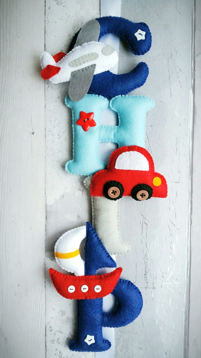 May include: Felt letter banner with the letters C, H, I, P, each decorated with a different transportation theme: airplane, car, sailboat, and a star. The letters are blue, light blue, gray, and dark blue.