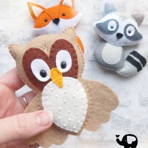 May include: Three felt animal toys: an orange fox, a gray raccoon, and a brown owl with white dots on its chest. The owl has a yellow beak and large black eyes. The toys are handmade and are part of a collection called "The Little Elephant".