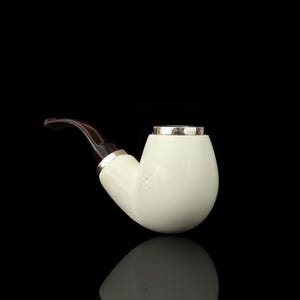 May include: A white tobacco pipe with a curved, dark brown stem. The pipe has a silver-colored band at the top and base of the stem. The pipe is set against a black background.