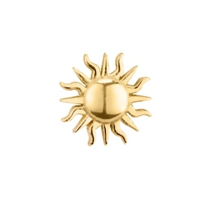 May include: A gold sun charm with a raised, round center and a detailed, textured design.