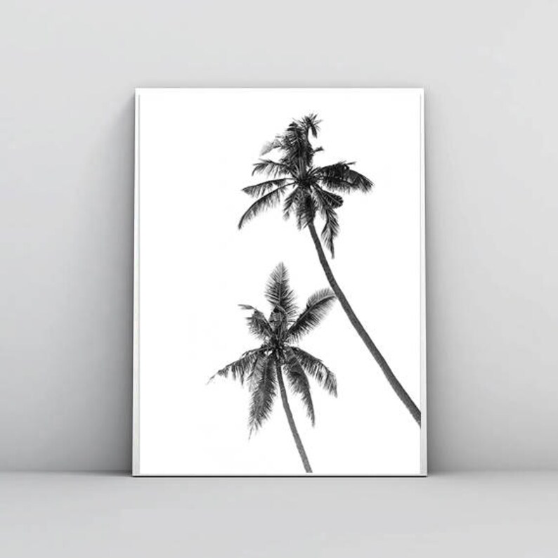 May include: Black and white print of two palm trees against a white background. The image features a minimalist design with the trees' silhouettes and fronds. The artwork is framed and ready to hang, suitable for coastal or tropical decor.