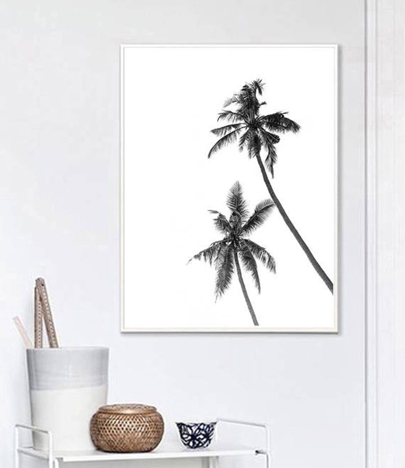 May include: Black and white framed print featuring two palm trees against a white background. The palm trees are detailed with dark fronds and trunks, creating a tropical aesthetic. The artwork is displayed in a white frame.
