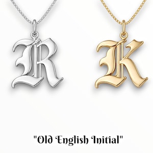 Puede incluir: Dos collares con colgantes de iniciales en estilo gótico. Un colgante es de tono plateado con cadena a juego, y el otro es de tono dorado con cadena a juego. El texto "Old English Initial" aparece debajo de las dos piezas de joyería.