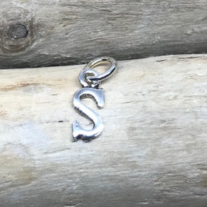 Op de afbeelding: Zilveren bedel in de vorm van de letter S. De bedel heeft een lus aan de bovenkant om aan een armband of ketting te bevestigen.