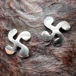 May include: Two silver metal earrings in the shape of a stylized four-leaf clover.