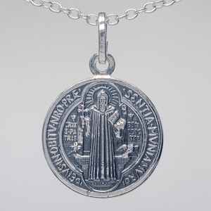May include: Silver St. Christopher medal pendant with a chain. The medal features a depiction of St. Christopher carrying the Christ child, with the inscription "S. CHRISTOPHORUS.  SANCTIA.  M.V.N.  DEVS.  VOBIS.  OBIIT.  ANNO.  PRO.  RE."