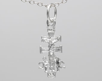 May include: A silver pendant necklace featuring a detailed cross with a figure of Jesus Christ on it. The cross has a decorative design with additional figures on the bottom.
