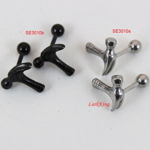 May include: Two pairs of hammer-shaped barbell earrings. One pair is black and the other is silver.