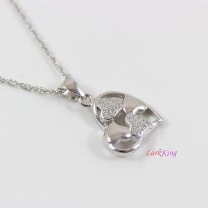 May include: A silver necklace with a pendant featuring two interlocking hearts, both adorned with small, clear cubic zirconia stones.