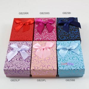 May include: Six small gift boxes with heart patterns and satin bows in various colors, including red, pink, blue, purple, and light blue. The boxes are labeled with the following codes: GB25RR, GB25MS, GB25BI, GB25LP, GB25PL, and GB25BB.