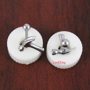 May include: Two silver hammer shaped earrings on white display stands. The earrings are made of surgical steel and have a ball at the top.