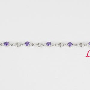 May include: A silver bracelet with a delicate chain and purple gemstones. The bracelet features a heart-shaped design.