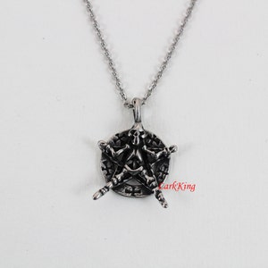 Puede incluir: Un collar de plata con un colgante de pentagrama con un dise&ntilde;o de calavera y huesos.