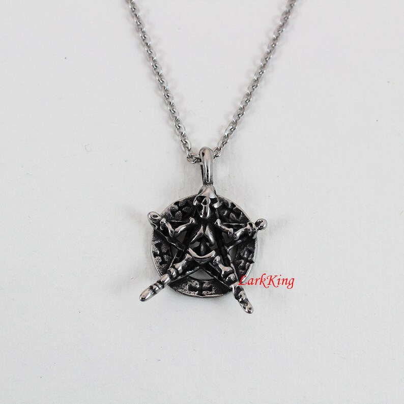 Puede incluir: Un collar de plata con un colgante de pentagrama con un dise&ntilde;o de calavera y huesos.