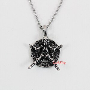 Puede incluir: Un collar con un colgante de plata que presenta una calavera en un dise&ntilde;o de pentagrama. El colgante est&aacute; detallado con un fondo texturizado y una cadena de eslabones.
