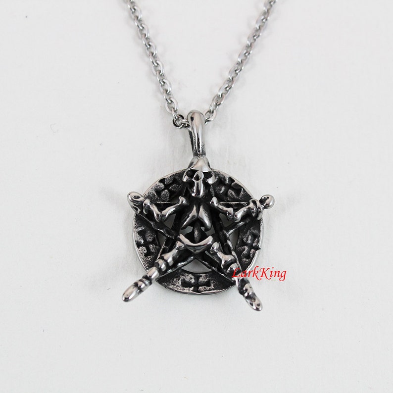 Puede incluir: Un collar con un colgante de plata que presenta una calavera en un dise&ntilde;o de pentagrama. El colgante est&aacute; detallado con un fondo texturizado y una cadena de eslabones.