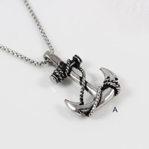 May include: A silver anchor necklace with a black rope detail. The anchor is a detailed design with a black rope wrapped around it.