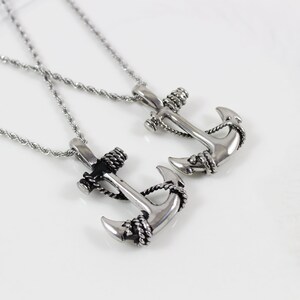 May include: Two silver anchor necklaces with rope detailing. The anchors are different sizes and are on silver chains.