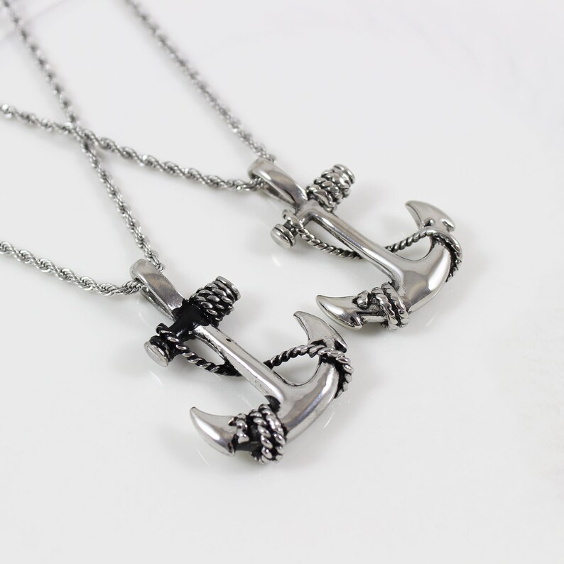 May include: Two silver anchor necklaces with rope detailing. The anchors are different sizes and are on silver chains.