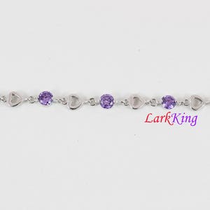 May include: A silver bracelet with a heart-shaped design and purple gemstones. LarkKing is printed on the bottom of the image.