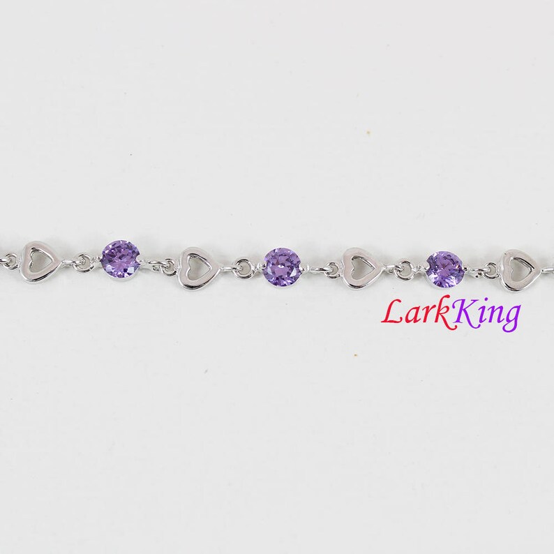 May include: A silver bracelet with a heart-shaped design and purple gemstones. LarkKing is printed on the bottom of the image.